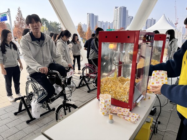 ▲ 자가발전 간식 만들기에서는 자가발전 수소 Science Class에 참가한 학생이 자전거를 이용해 운동에너지 를 전기로 변환해 기계를 작동, 팝콘을 만드는 체험을 하고 있다.